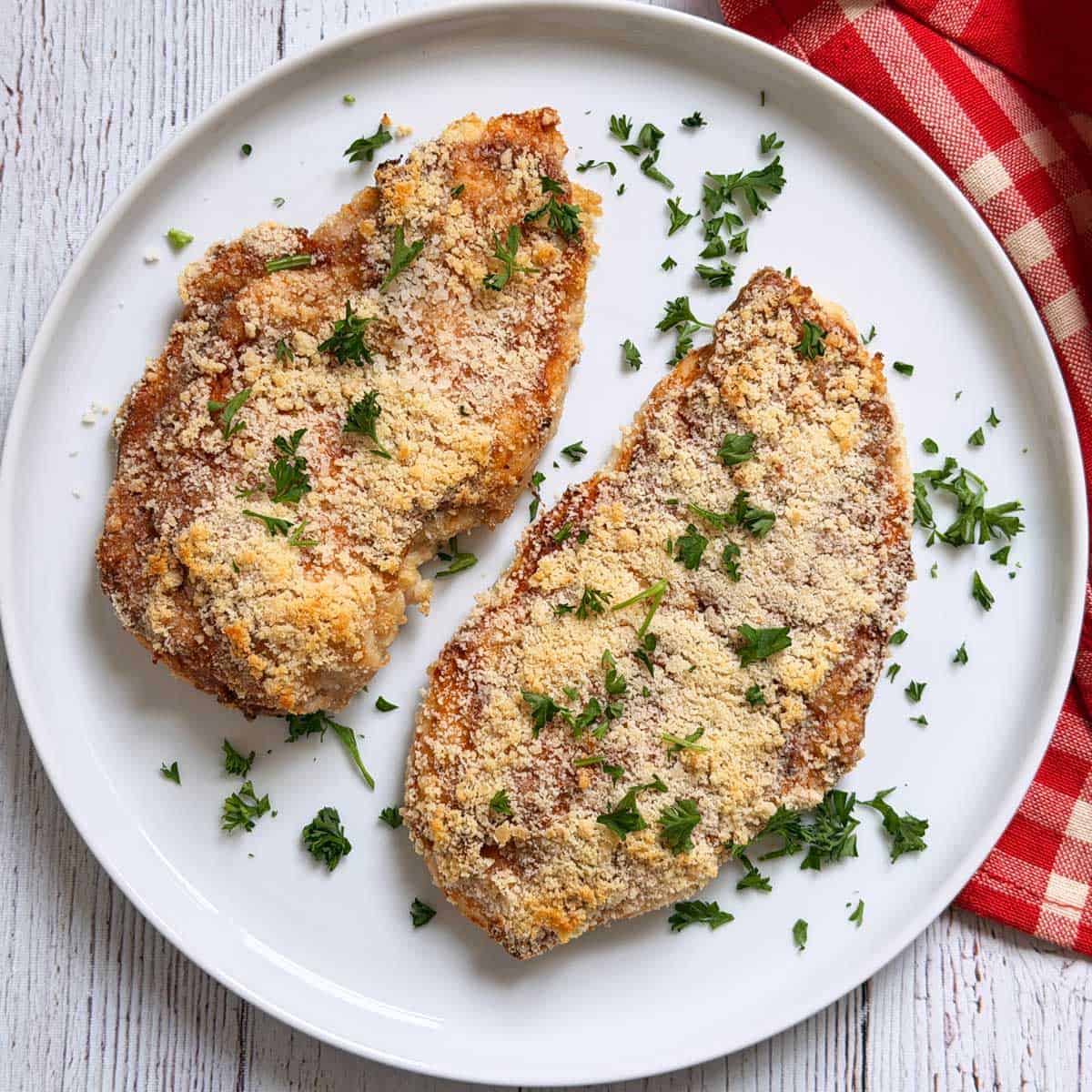 Parmesan crusted chicken is served on a white plate.