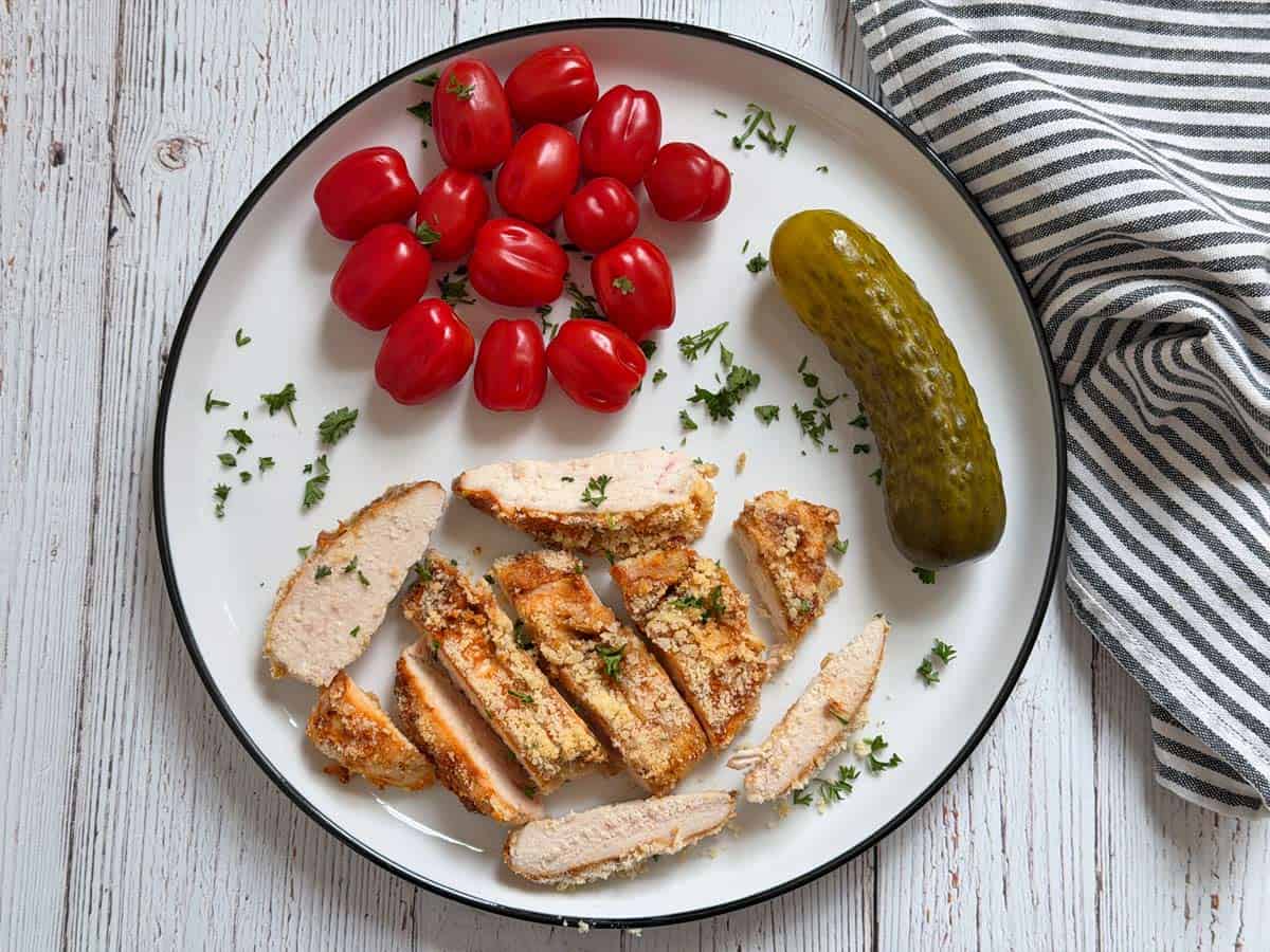 Parmesan crusted chicken leftovers are served with tomatoes and pickles.