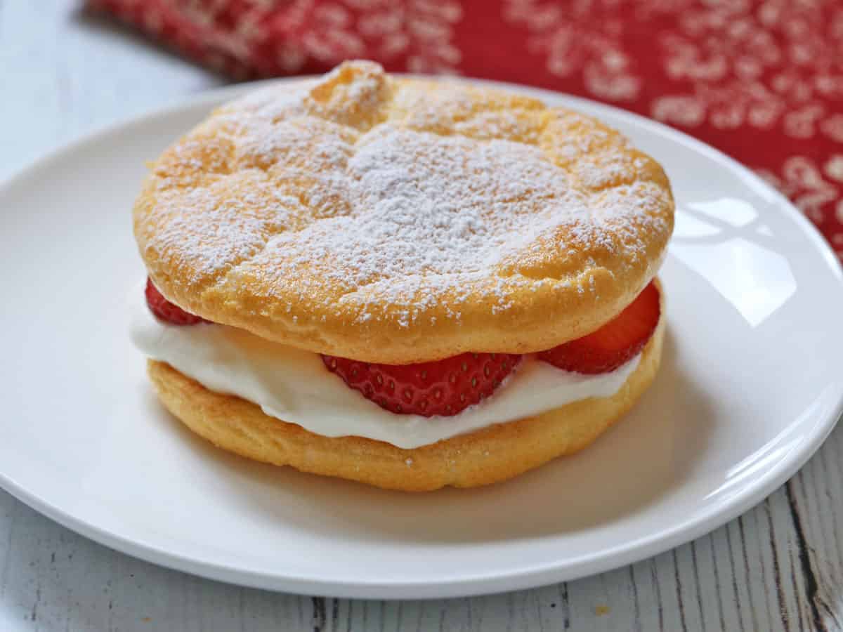 Keto strawberry shortcake made with cloud bread is served on a white plate.